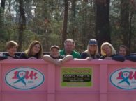 A group of people standing behind a pink fence.