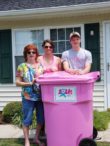 A family standing next to a pink trash can.